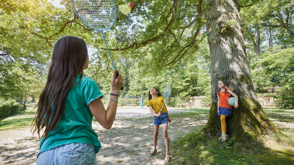 3 children playing badminton in the recreation area