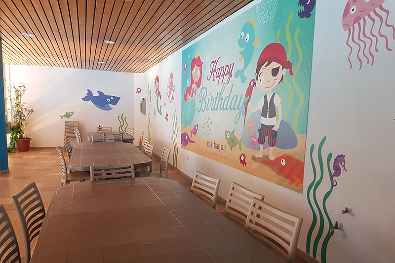 Room for the birthday party, view of tables and chairs, ‘Happy Birthday’ poster on the wall.